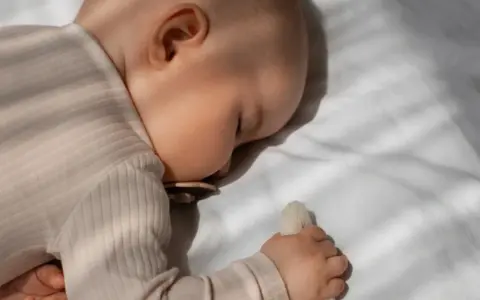 Bambino dorme sereno, forse grazie alla melatonina per bambini iperattivi, con ciuccio e peluche.