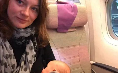 Kobieta karmi niemowlaka podczas lotu samolotem.