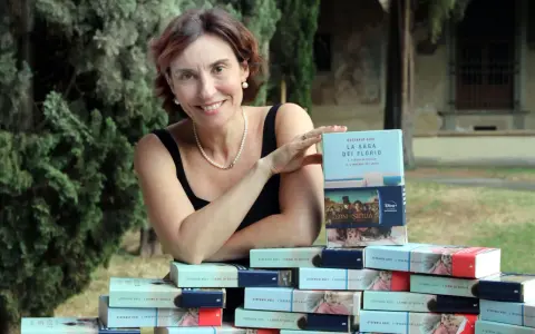 Stefania Auci sorride, circondata dai suoi libri "I Leoni di Sicilia" e "L'inverno dei leoni", celebrando il successo della saga.