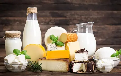 Milchprodukte wie Käse und Milch, die Laktose enthalten, sind auf einem Holztisch arrangiert.
