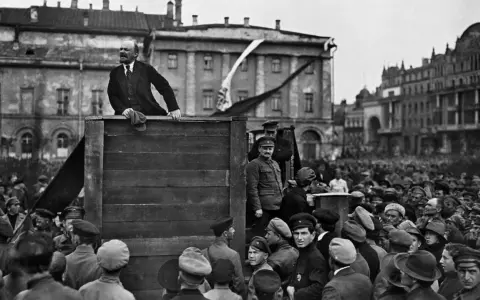 Lenin spricht von einer improvisierten Bühne zu einer großen Menschenmenge. Die Szene wirkt wie eine "revolution von oben", die das Volk mobilisiert.