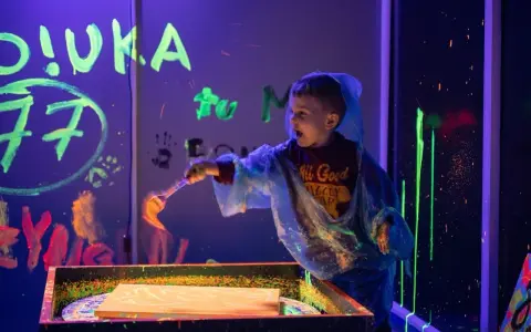 Chłopiec w neonowych barwach tworzy sztukę w ciemni. Świetne atrakcje dla dzieci w Szczecinie!
