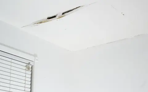 Widoczne pęknięcia na suficie w starym domu, świadczące o jego wieku i potrzebie remontu.