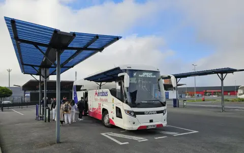 Autobus Aerobus Paris-Beauvais czeka na pasażerów pod niebieskim zadaszeniem.