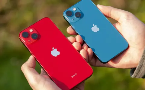 Dwie dłonie trzymają dwa telefony: czerwony i niebieski iPhone 13 mini. Aparat obu modeli jest widoczny.