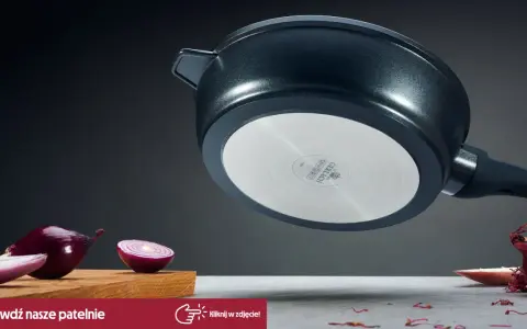 Patelnia żeliwna z metalowym dnem, obok czerwonej cebuli na desce.