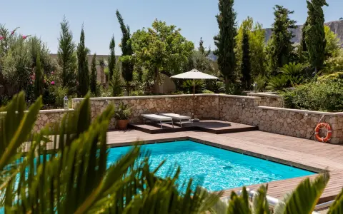 Piscine luxueuse avec terrasse en bois, transats, parasol et bouée. La protection électrique de la piscine est assurée pour une baignade en toute sécurité.