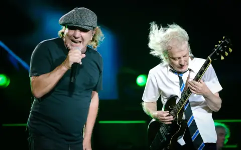 Brian Johnson śpiewa, Angus Young gra na gitarze podczas jednego z legendarnych **AC/DC koncertów**.