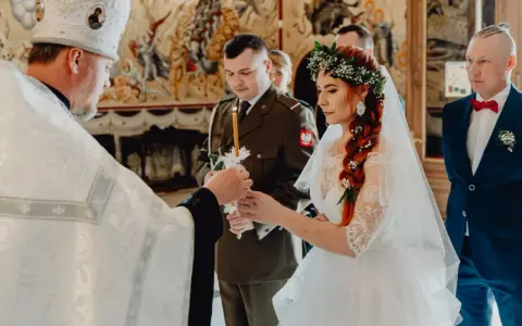 Uroczysty ślub prawosławny. Panna młoda w wianku, pan młody w mundurze, kapłan zapala świece.