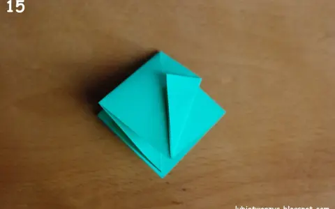 Krok 15 instrukcji, jak zrobić kwadrat z papieru. Turkusowa origami na drewnianym tle.