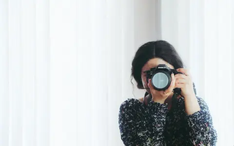 Kobieta z aparatem Canon, skupiona na kadrze. Rozwija swój biznes fotograficzny, łapiąc chwile.