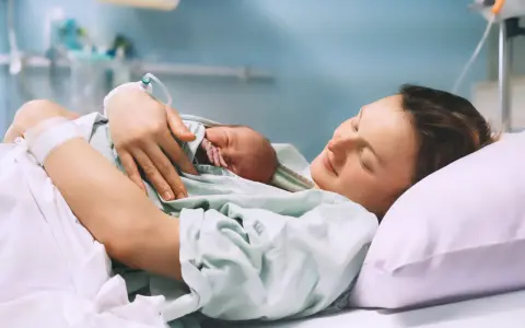 Szczęśliwa mama tuli noworodka po porodzie, czując ulgę po znieczuleniu.