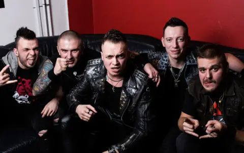 Pięciu mężczyzn w skórzanych kurtkach i z rockowymi fryzurami, jakby gotowi na nocny koncert. Wyglądają jak zespół nocny kochanek.