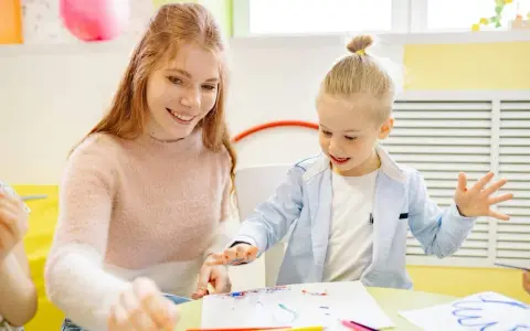 Uśmiechnięta kobieta i chłopiec malują. Wspólne tworzenie to klucz do tego, jak budować relacje z dzieckiem.