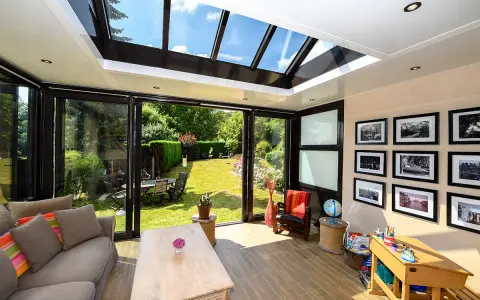 Un salon lumineux avec un canapé confortable, une table basse en bois, et une vue imprenable sur un jardin verdoyant depuis cette **veranda interieur**.