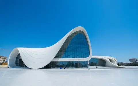 Impresionante centro de congresos con fluidas estructuras diseñadas por Zaha Hadid, bajo un cielo azul intenso.