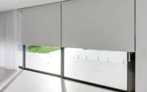Elegantes persianas enrollables grises ofrecen soluciones para ventanas con mucho sol, bloqueando el deslumbramiento y el calor.