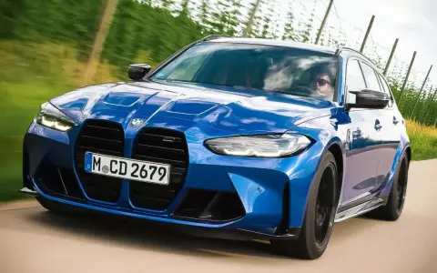 Blauer BMW M3 Competition Kombi rast auf einer Landstraße, die Sonne spiegelt sich im Lack.