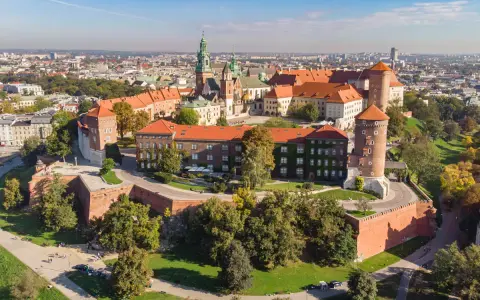 Wawel w Krakowie, z charakterystyczną wieżą widokową, otoczony zielenią i zabytkową architekturą.