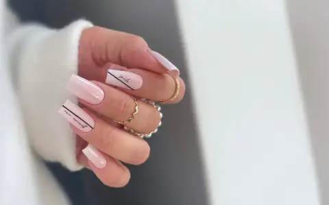 Delikatne, **milky nails** w odcieniach różu, ozdobione czarnymi napisami "smile" i "our moment".