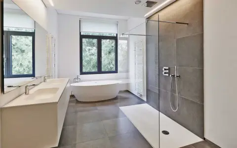 Salle de bain moderne avec douche à l'italienne aux galets hydrofuges, baignoire îlot et double vasque.