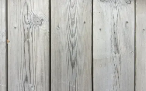 Grå träplankor på en kisel altan i Sverige. Vackert åldrat trä med synliga ådringar och kvistar.