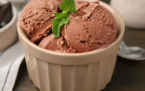 Schokoladeneis in einer Schale, garniert mit Minze. Dieses Eis ist ein Beweis dafür, was vollrahm ist: cremig, reichhaltig und unwiderstehlich.
