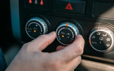 Dłoń kręci pokrętłem klimatyzacji, próbując zdiagnozować objawy zepsutego termostatu.