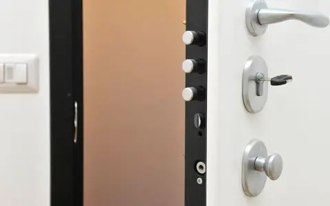 Detalle de una puerta de seguridad con varios tipos de cerraduras y un cerrojo con llave.