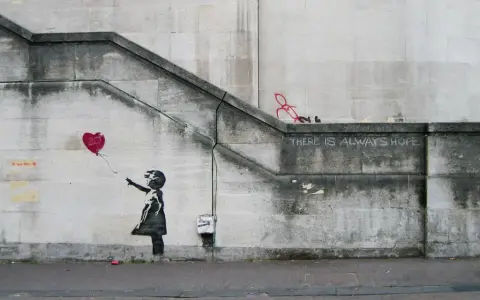 La célèbre œuvre de Banksy, "Girl with Balloon", sur un mur de pierre. Une petite fille lâche un ballon en forme de cœur rouge.