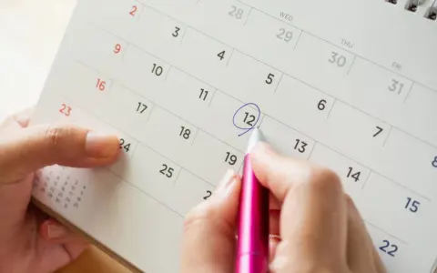 Dłoń zaznacza datę na kalendarzu, symbolizującą długie i obfite miesiączki w okresie menopauzy.