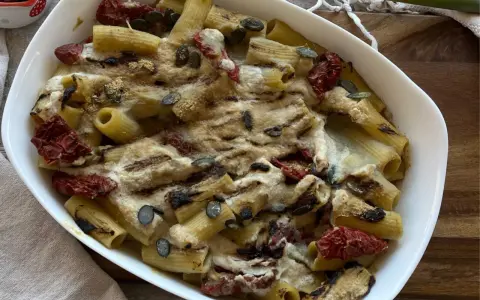 Piatto di pasta con carciofi alla siciliana, pomodori secchi e semi di zucca, gratinata al forno.