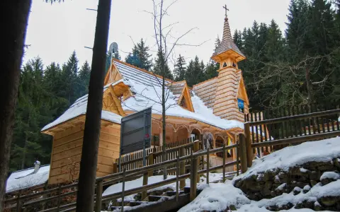 Drewniany kościółek, najwyżej położony kościół w Tatrach, otoczony ośnieżonym lasem.
