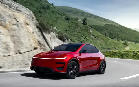 Czerwony Tesla Model Y Performance na krętej drodze w górach.