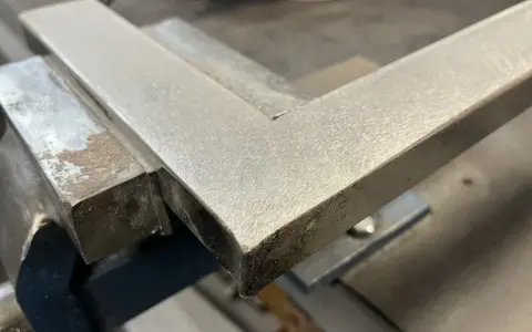 Un ángulo metálico en una escuadra de carpintero, listo para ser pulido con herramientas de acabado.