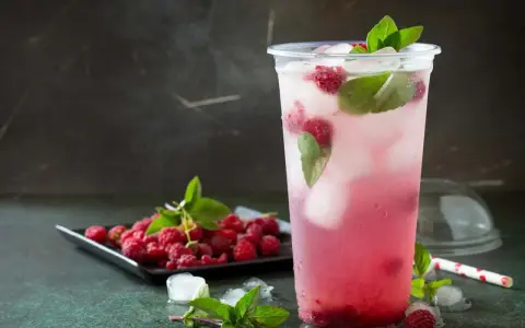 En uppfriskande raspberry daiquiri med färska hallon och mynta, serverad i ett plastglas med is.