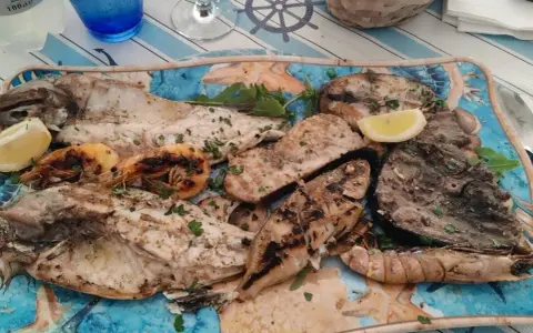 A platter of grilled fish and shrimp garnished with lemon and parsley.
