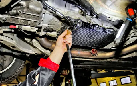 Mechanik wykonuje wymianę oleju w skrzyni automatycznej, używając specjalistycznego sprzętu do serwisu.