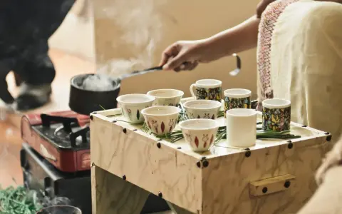 Tradycyjna ceremonia parzenia kawy, która pokazuje, skąd pochodzi kawa. Dym unosi się z małego czajniczka, a filiżanki czekają na aromatyczny napój.