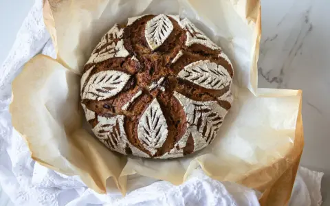 Chleb na zakwasie z pięknym wzorem liści, pieczony na papierze, który świetnie sprawdza się co zamiast papieru do pieczenia.