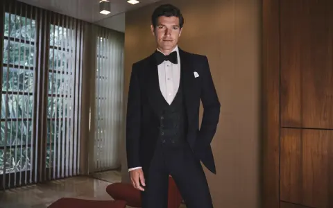 A man in a tuxedo, embodying the perfect gala dinner dress code male attire, stands confidently.