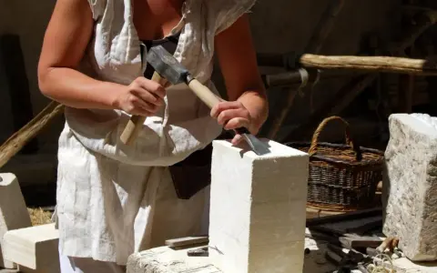 Un artisan tailleur de pierre travaille la pierre avec un marteau et un ciseau.