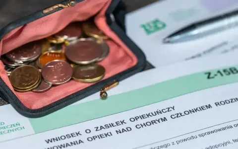 Portmonetka z monetami leży obok formularza ZUS Z-15B, który dotyczy wniosku o zasiłek opiekuńczy.