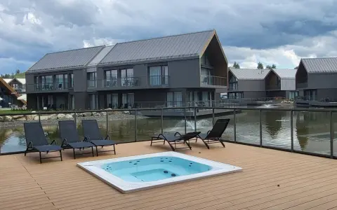 Relaks przy jacuzzi i basenie z widokiem na nowoczesne domki nad wodą. Idealne miejsce na wypoczynek w stylu termy Karkonosze.