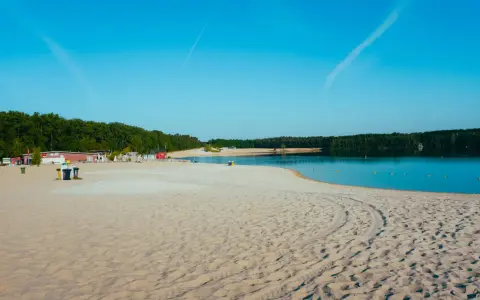 Sonniger Strand in NRW mit feinem Sand, klarem Wasser und grünen Bäumen im Hintergrund. Perfekt für einen entspannten Tag am See.