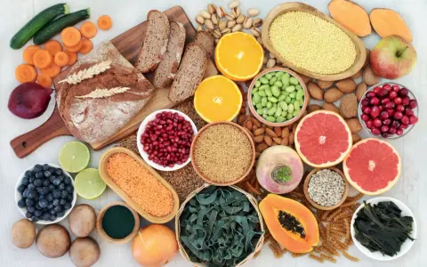 Vielfalt an ballaststoffe produkten: Vollkornbrot, Linsen, Beeren, Nüsse, Obst und Gemüse für eine gesunde Ernährung.