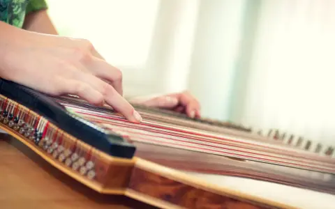Hände spielen auf einem Hackbrett, das vielleicht das einfachste Instrument ist, um Melodien zu erzeugen.