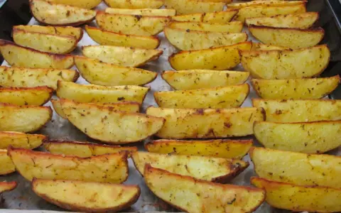 Des pommes de terre rôties au four croustillantes, dorées et assaisonnées, disposées sur une plaque de cuisson.