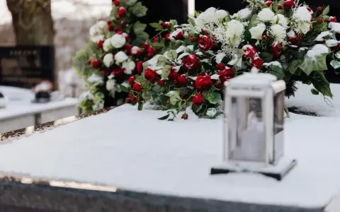 Wieniec dla taty: czerwone róże i białe kwiaty na śniegu, obok lampion.