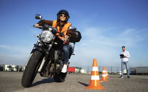 Joven sonriente en moto, lista para obtener el carnet de moto 49cc. Instructor observa en el fondo.